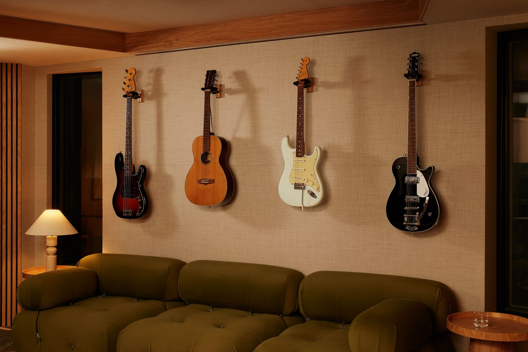 Four guitars hung above a green velvet sofa